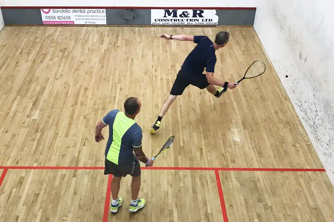 Two squash players near the front of the court playing a conditioned game.
