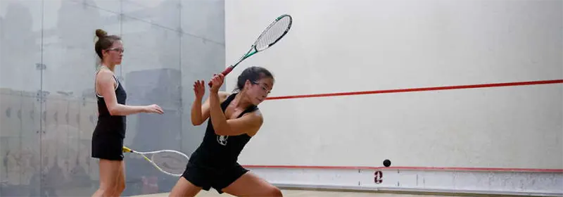 Two female squash players on a glass court