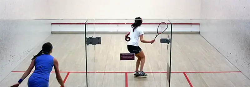 Two femalke squash players in the middle of a rally