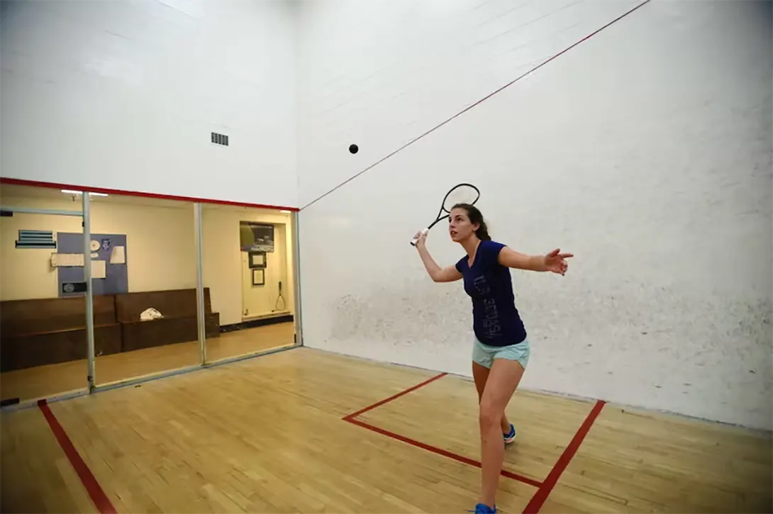 A young woman about to serve on her forehand