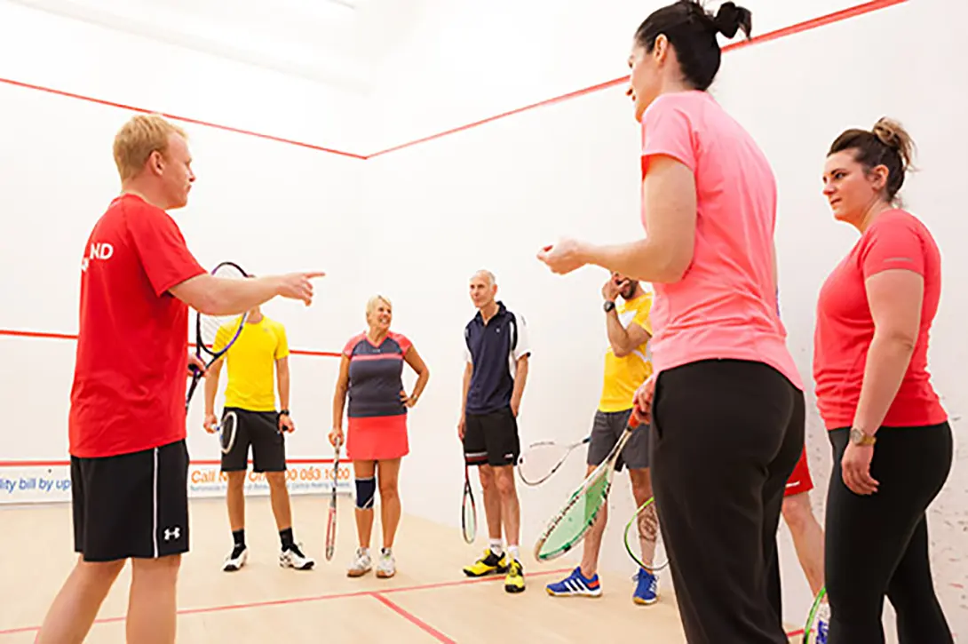 A squash coach talking to a group of pupils