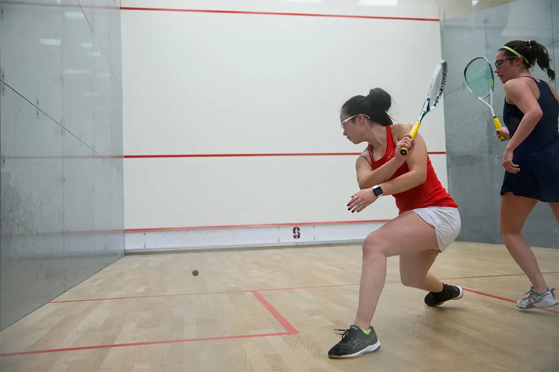 Two female squash players in the middle of a rally