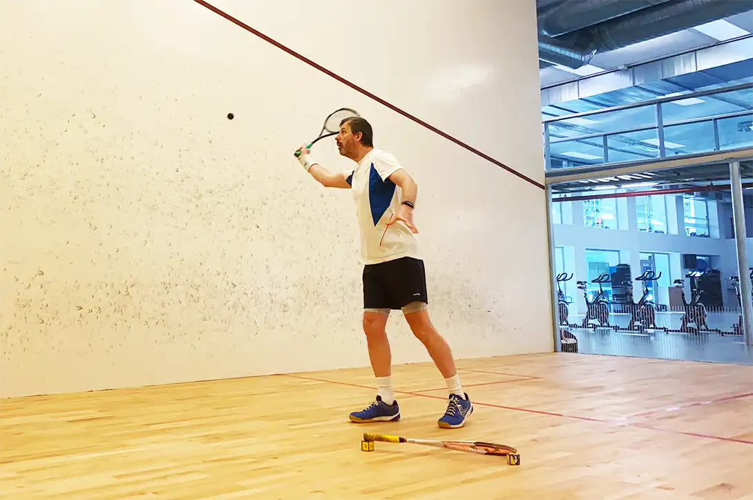 A very handsome, intelligent and modest man practising his volley kills on a squash court