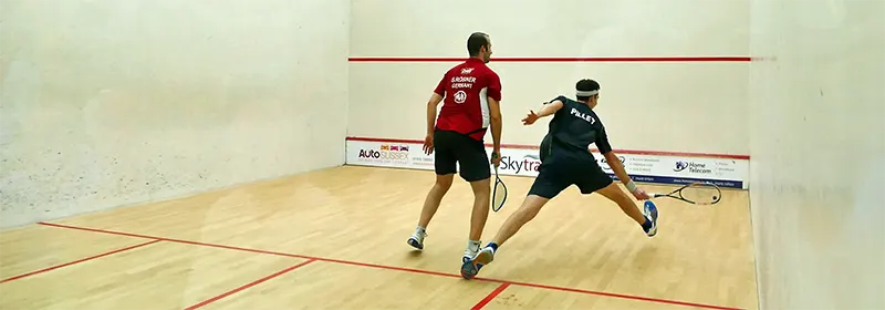 Two professional squash players in the middle of a rally
