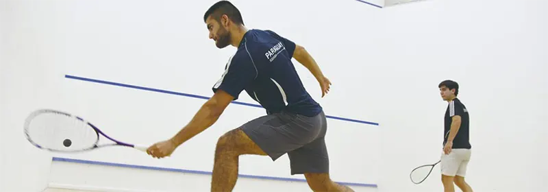 Two men hitting the ball back to each other on a squash court