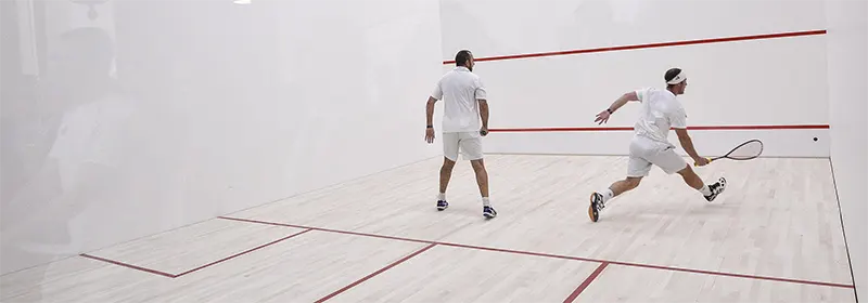Two squash players in the middle of a tough rally