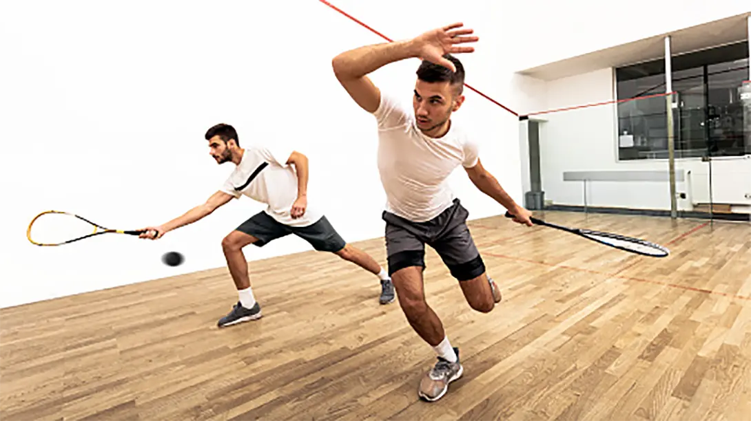 Two men playing squash as if they are on cocaine!
