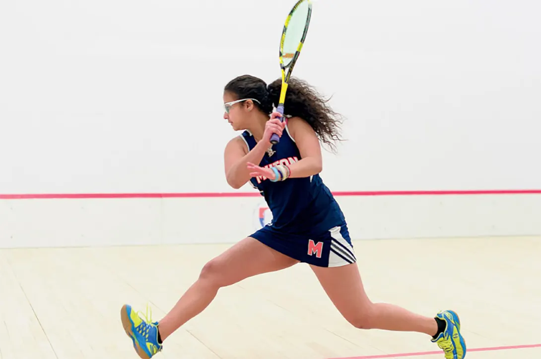 A female squash player about to hit the ball hard
