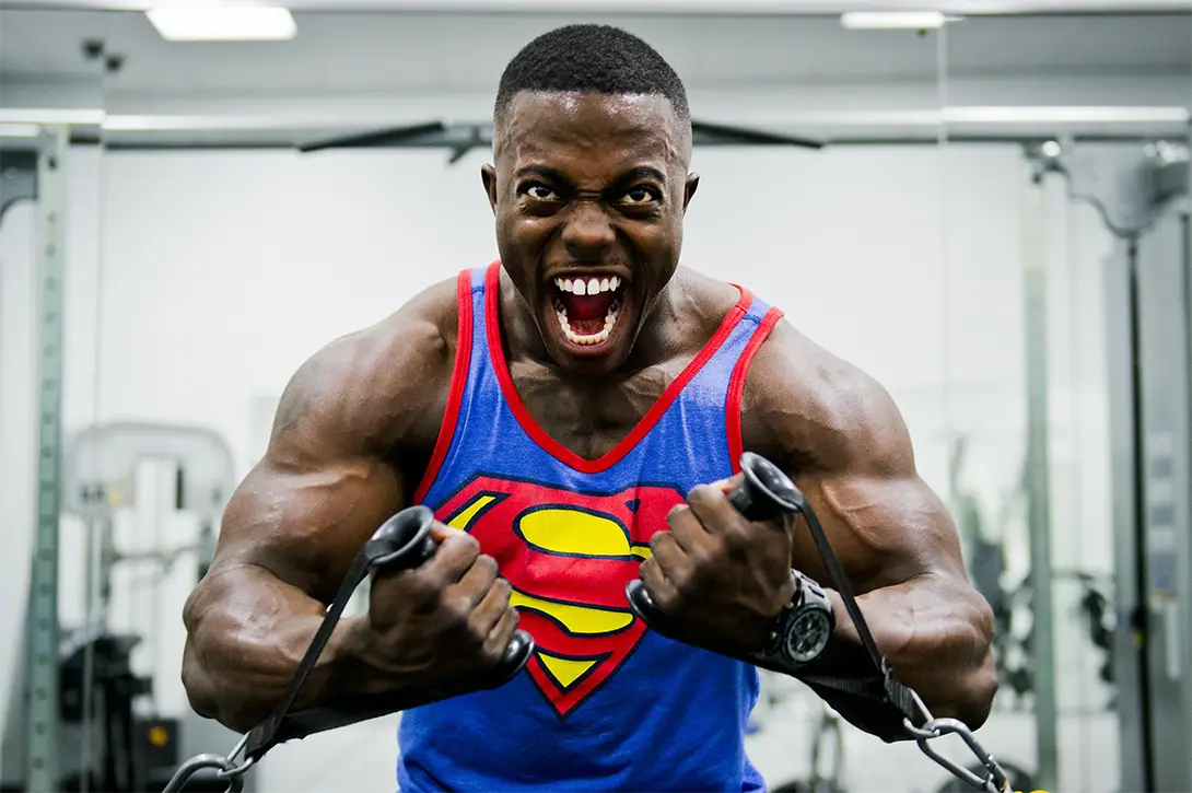 Man wearing a Superman vest using cable weights