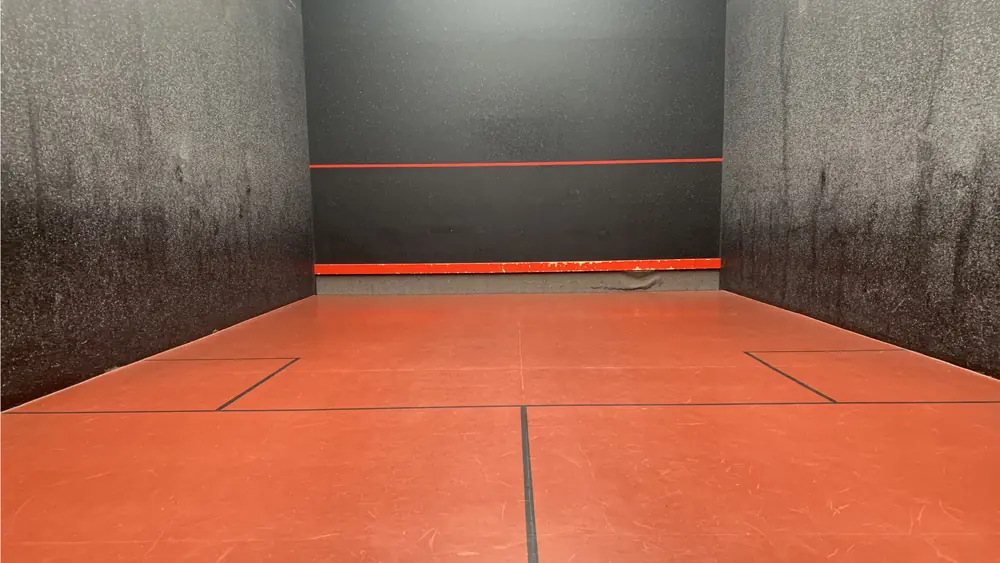 The beautiful red floor and black walls of Wellington Rackets Court in Berkshire