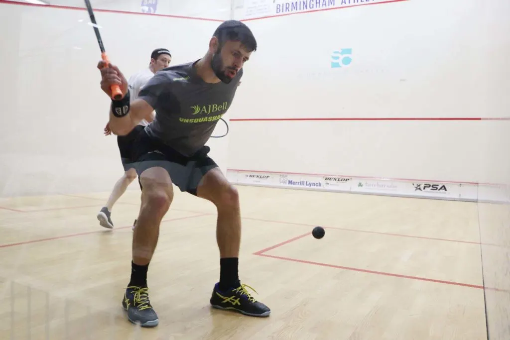 A squash player in the righ-hand back corner ready to play a shot